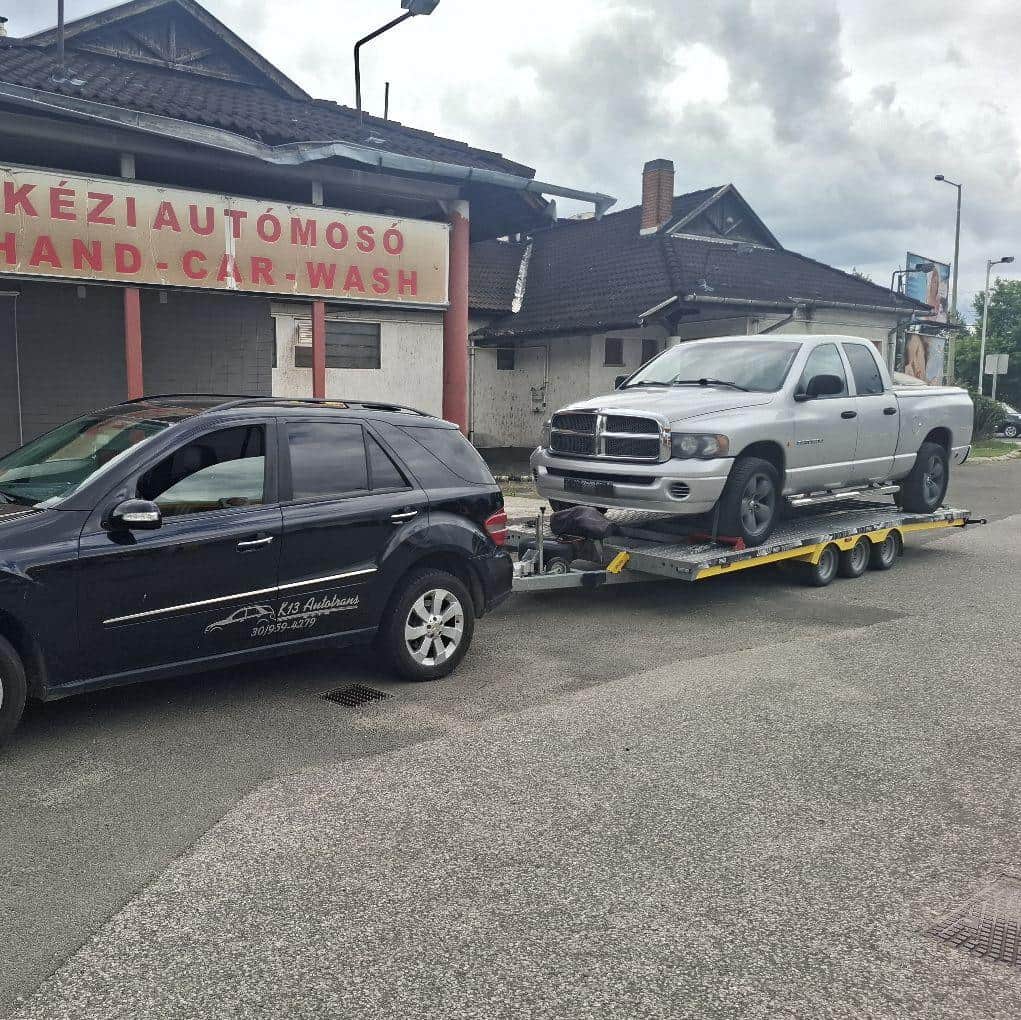 Ezüst Dodge Ram pickup szállítása tréleren egy autómosó előtt