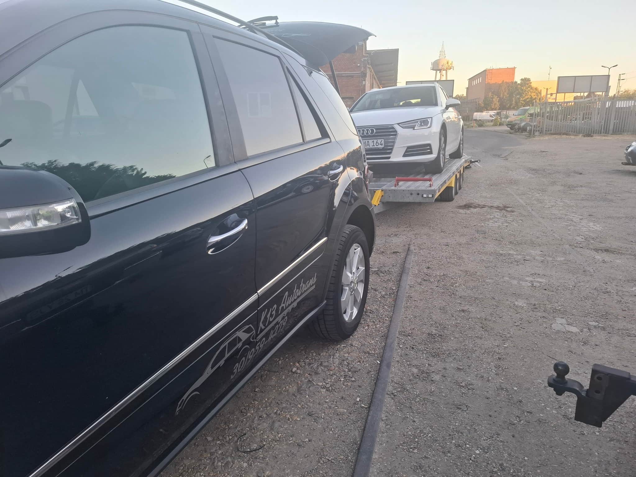 K13 Autotrans feliratos fekete Mercedes vontató, mögötte fehér Audi a trélerre rakva